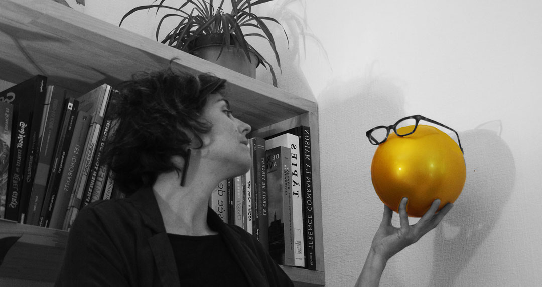 Amélie Clergeau, portrait en noir et blanc et touche de couleur sur la balle - souvenir Portrait photo d'Amélie Clergeau en noir et blanc avec balle dorée devant bibliothèque - mot conte double