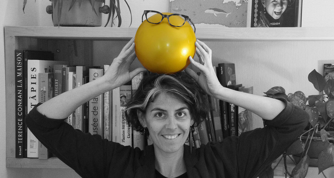 Portrait photo d'Amélie Clergeau en noir et blanc avec balle dorée devant bibliothèque - mot conte double
